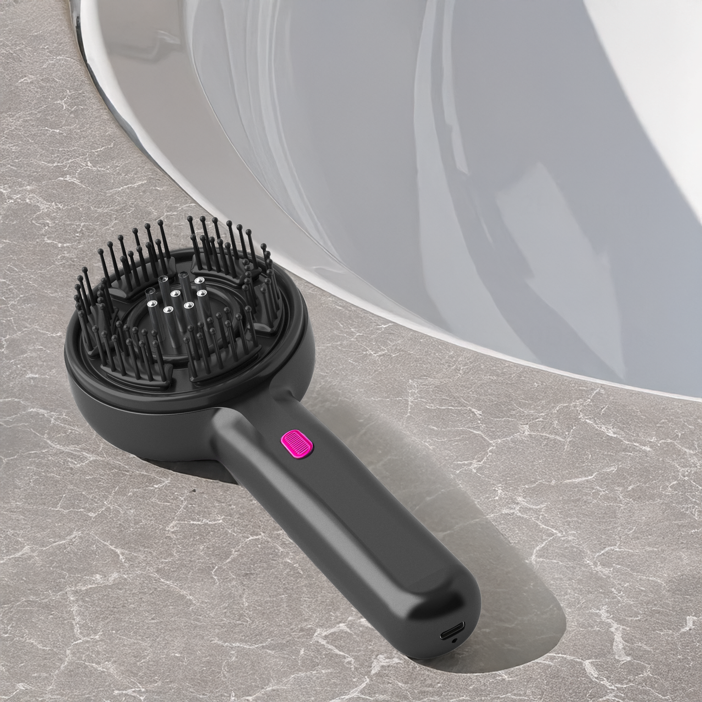 Black hairbrush with bristle head and pink button on a gray surface